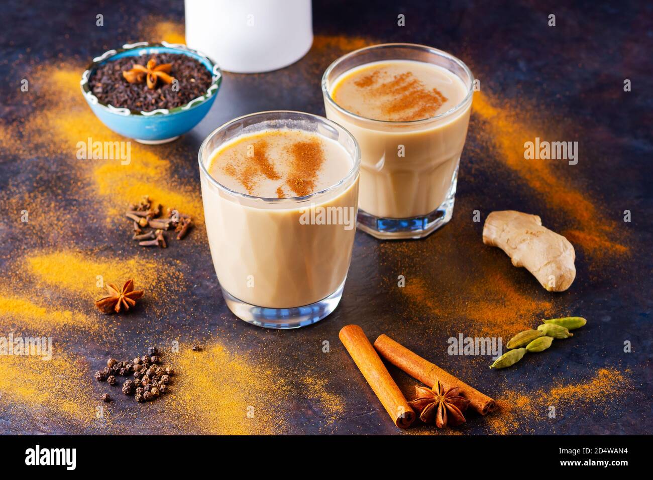 Masala chai thé et pot à lait sur fond noir. Deux verres de thé masala et épices éparses. Vue de dessus Banque D'Images