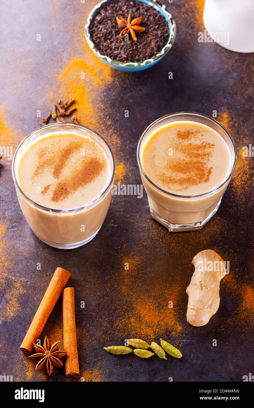 Masala chai thé et pot à lait sur fond noir. Deux verres de thé masala et épices éparses. Vue de dessus Banque D'Images
