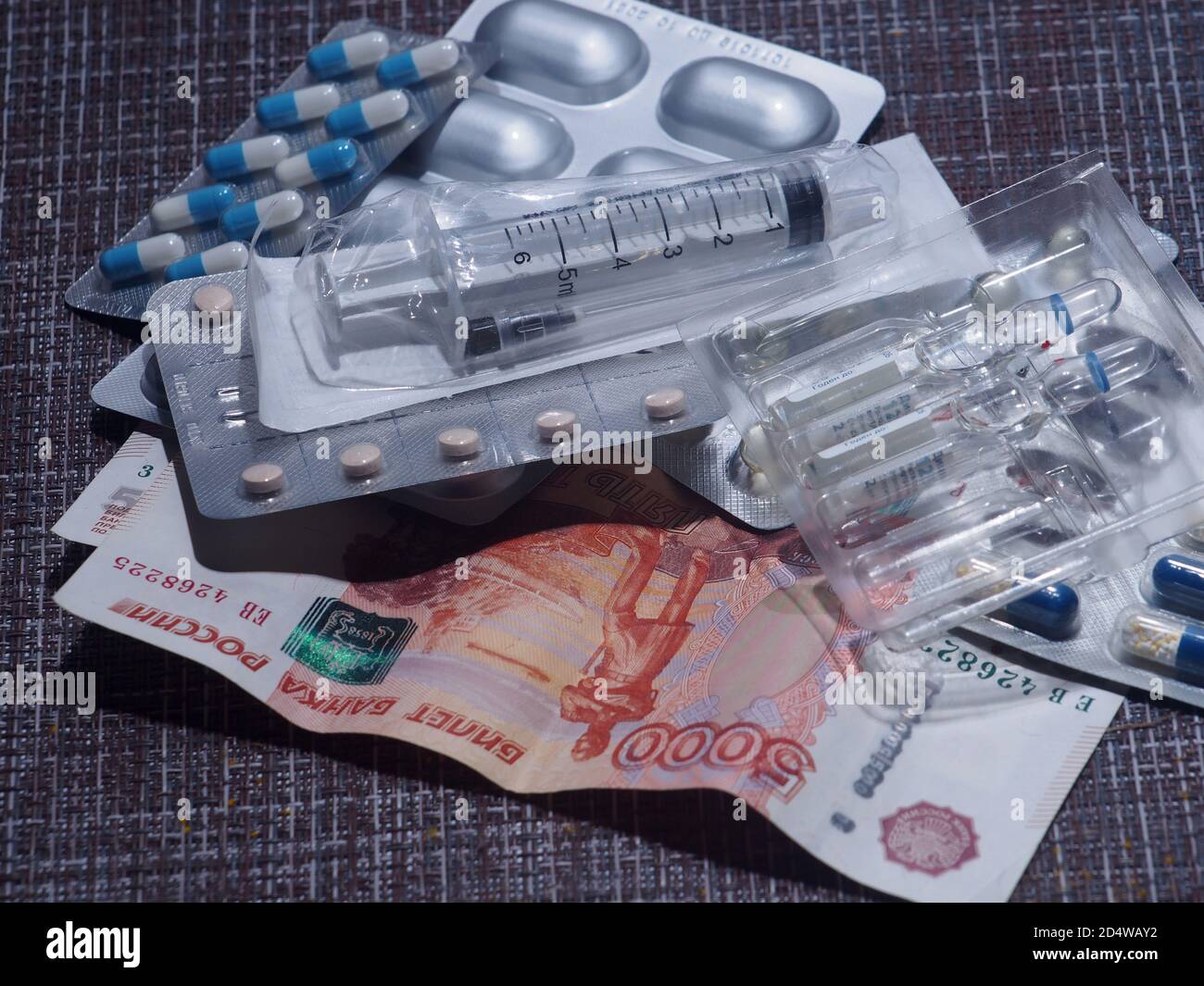 Sur la table se trouvent des pilules, des capsules et des ampoules avec des médicaments, une seringue et des rubles russes. Gros plan. Banque D'Images