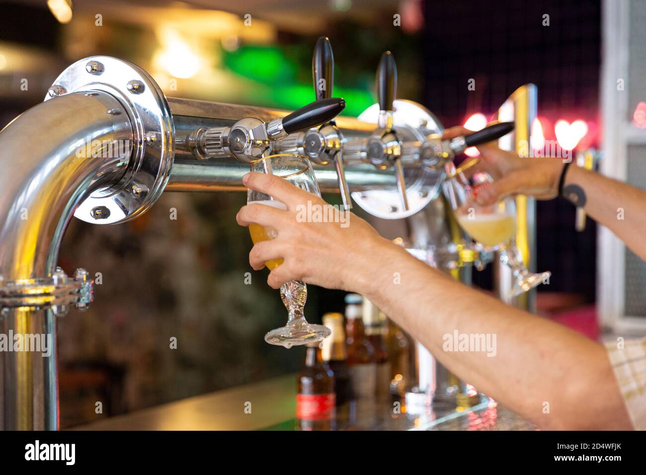 Gros plan des mains d'une personne remplissant deux tasses à bière à la fois dans un bar. Mise au point sélective. Banque D'Images