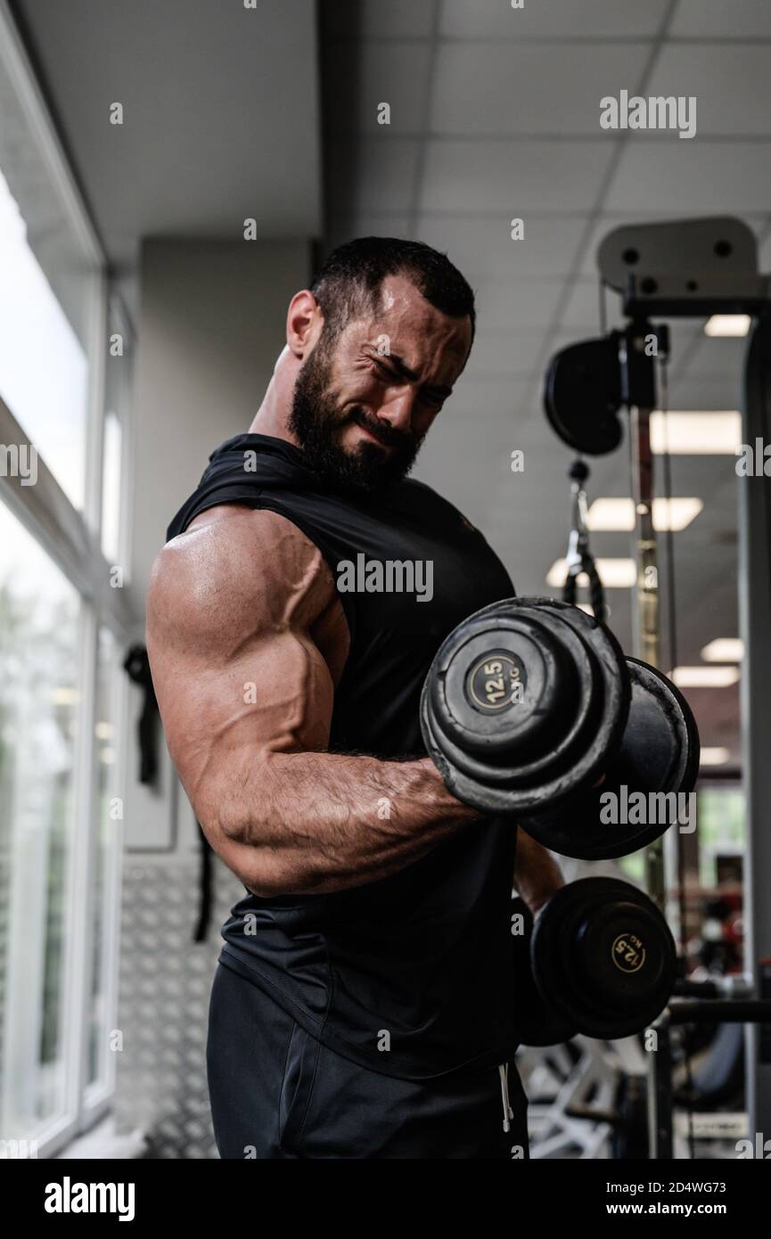 motivation d'entraînement de musculation intense de jeune homme barbu fort  fer de levage poids lourd haltères pendant l'entraînement de muscle de  biceps dans sport Photo Stock - Alamy