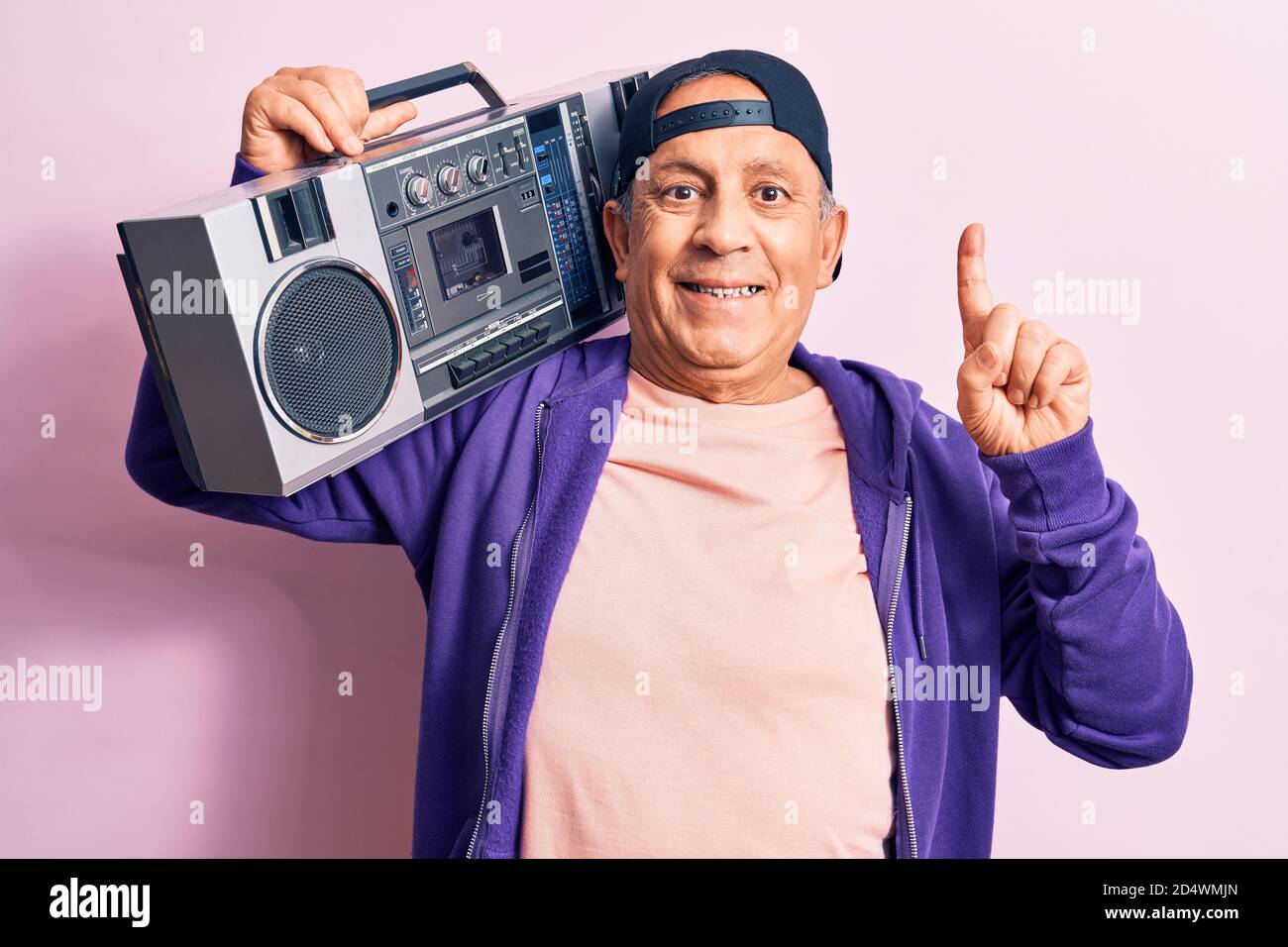 Senior beau gris-cheveux moderne homme à l'écoute de la musique à l'aide de boombox vintage souriant avec une idée ou une question pointant du doigt avec le visage heureux, engourdi Banque D'Images