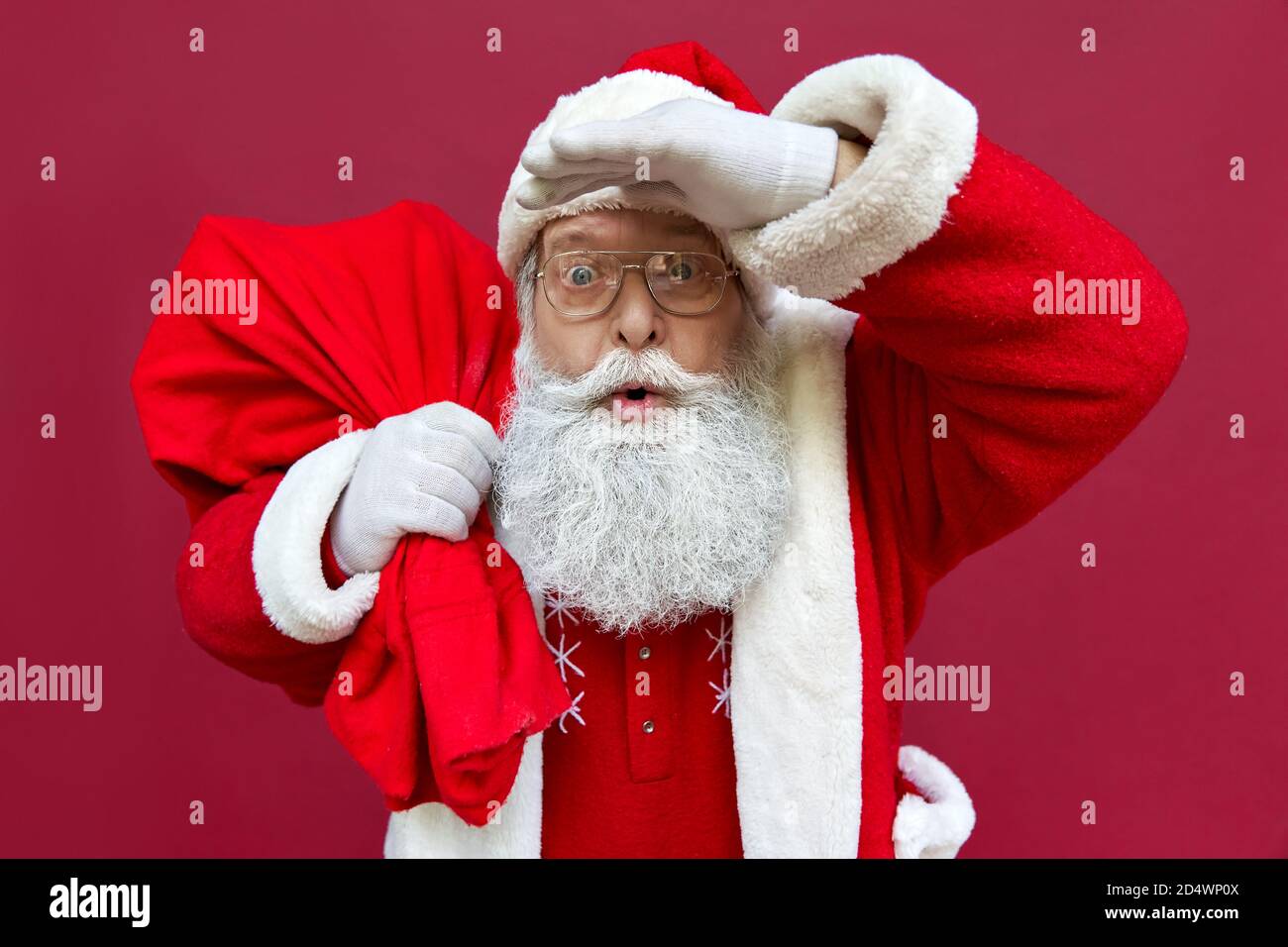 Surprise le père Noël choqué sac de maintien avec des cadeaux de Noël  isolés sur le rouge Photo Stock - Alamy