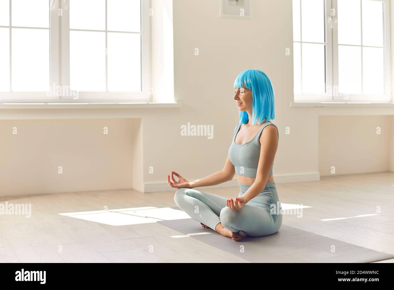 Jeune fille assise en position facile sur le tapis de yoga avec les yeux fermés pratiquant la méditation seule Banque D'Images