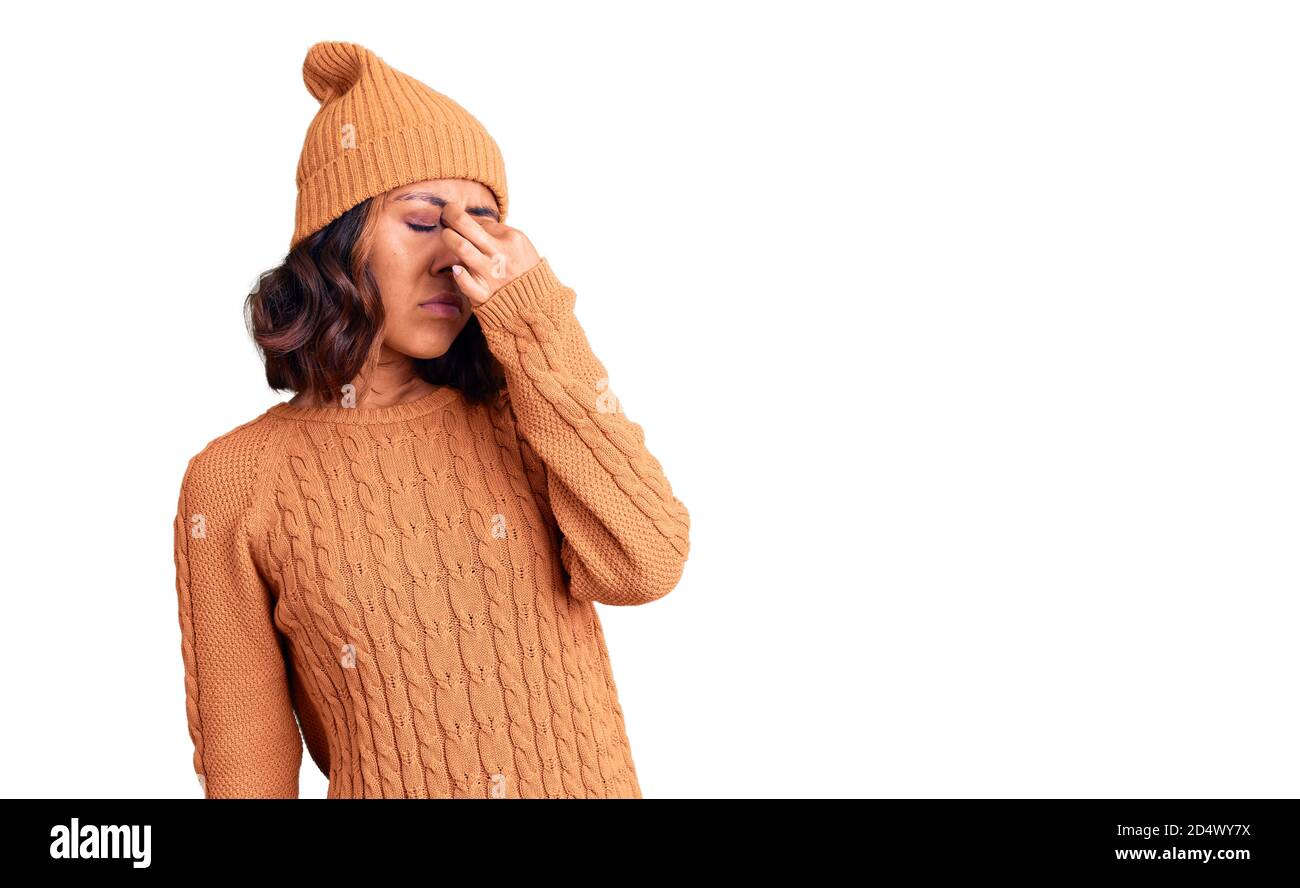 Jeune belle femme de course mixte portant un pull en laine et chapeau d'hiver fatigué frottant nez et yeux sensation de fatigue et de maux de tête. Stress et frustration Banque D'Images