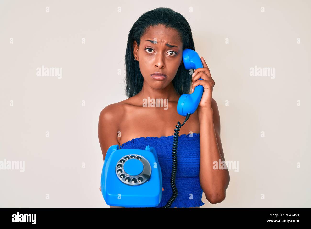 Jeune afro-américaine tenant le téléphone vintage déprimé et s'inquiéter de la détresse, pleurant en colère et peur. Expression triste. Banque D'Images