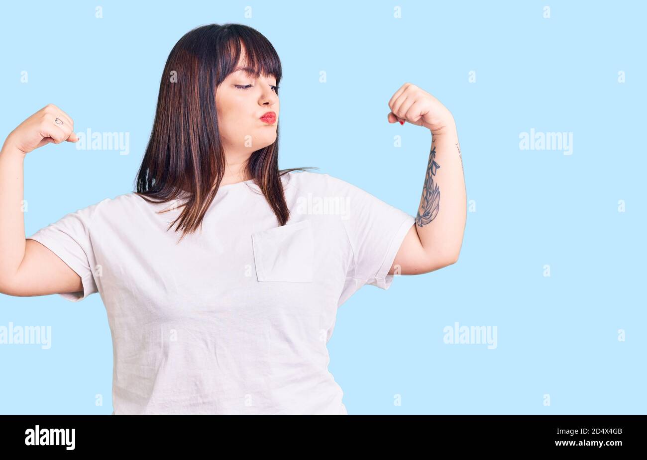 Jeune femme de taille plus portant des vêtements décontractés montrant les bras muscles souriant fier. Concept de forme physique. Banque D'Images