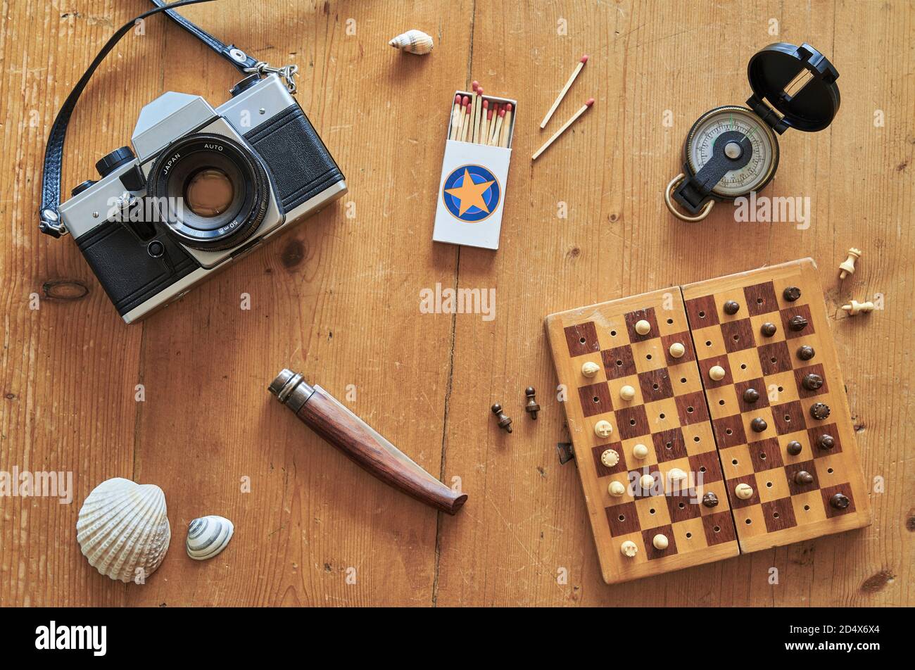 Vue de dessus de l'équipement de voyage rétro sur une table en bois. Appareil photo vintage, allumettes, couteau, moule, échiquier et boussole sur une table en bois. Banque D'Images