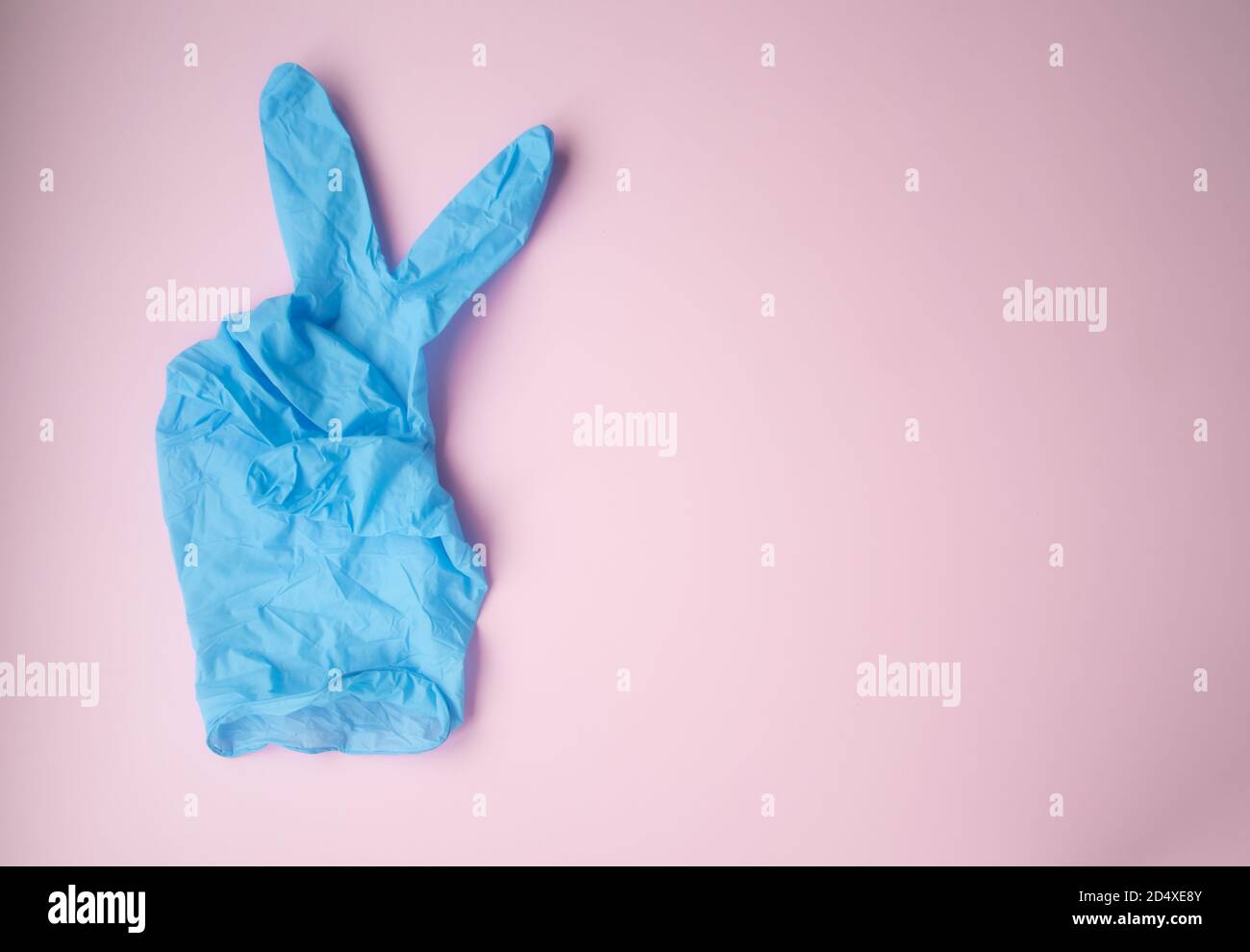 La marque V est représentée par un gant médical bleu sur fond rose. Symbole de victoire. Vaincre le virus. Banque D'Images