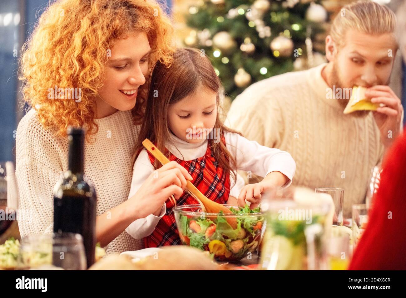 Famille assise derrière la table avec une salade fraîche Banque D'Images