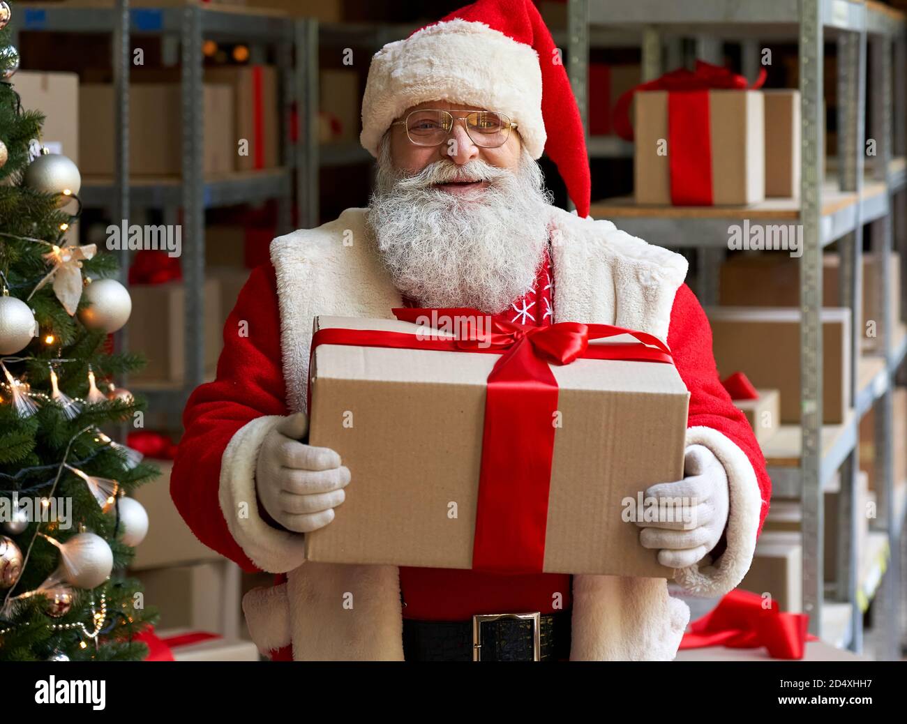 Joyeux Père Noël portant un costume tenant une boîte cadeau dans un  atelier, portrait Photo Stock - Alamy
