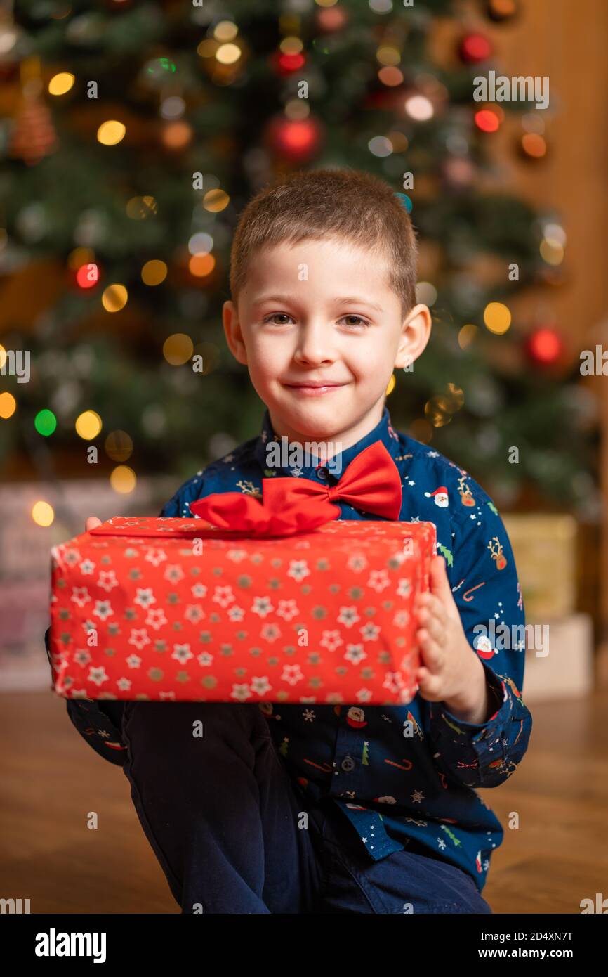 Noël fabuleux, petit garçon tenant une grande boîte rouge avec un cadeau de Santa. Banque D'Images