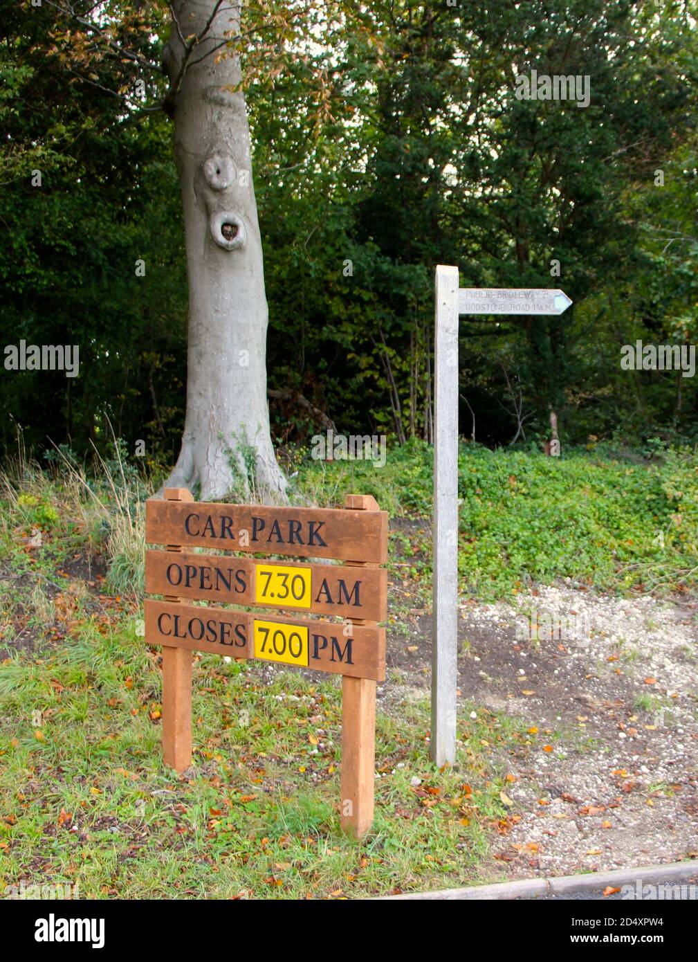Horaires d'ouverture du parking sur un panneau en bois et un poteau avec une flèche et les distances dans Miles Riddlesdown Surrey Angleterre Royaume-Uni Banque D'Images