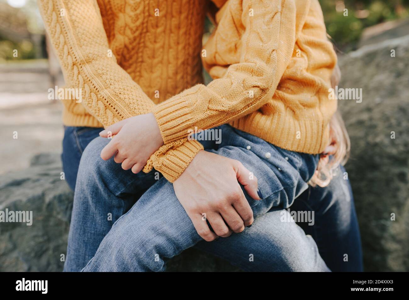doux câlin de parent et d'enfant vêtu de la même tenue. chaud vêtements tricotés d'automne : chandail jaune et jeans bleus. promenades d'automne dans l'air frais Banque D'Images