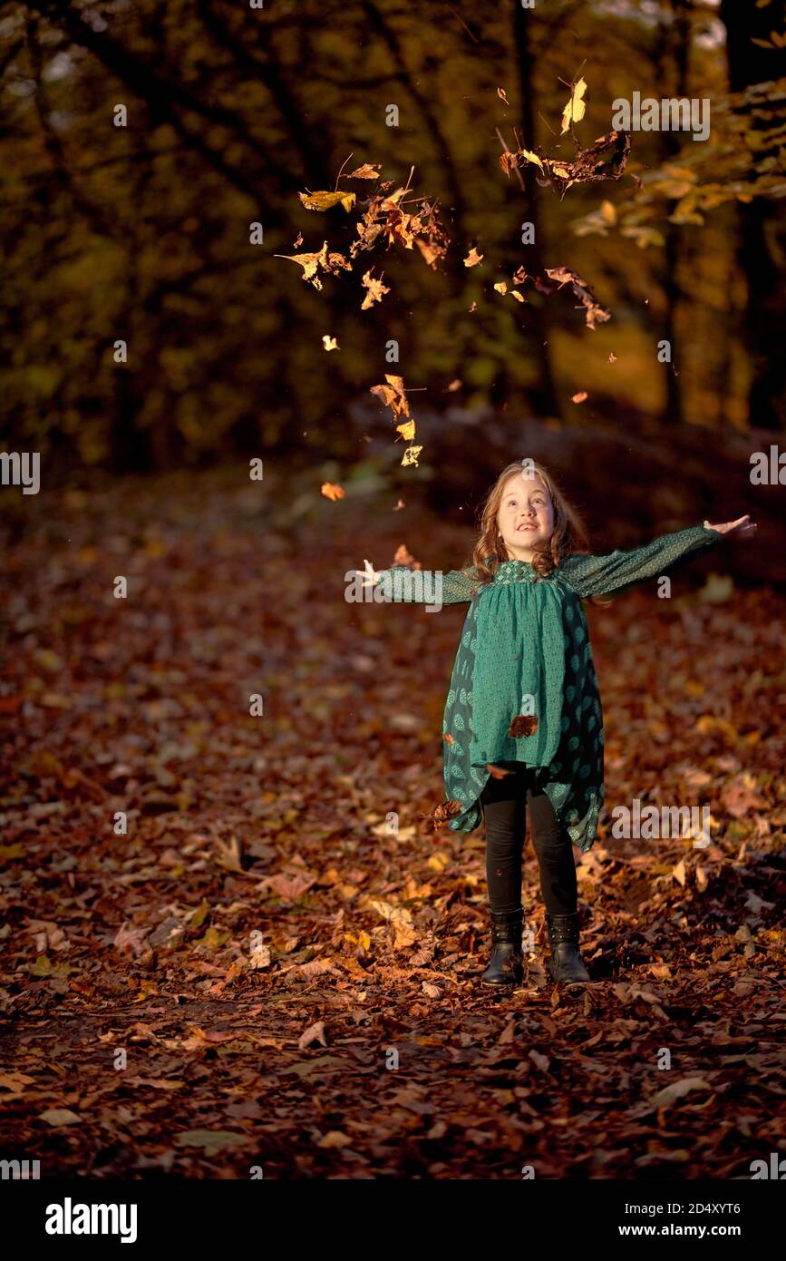 fille de 7 ans jetant des feuilles dans l'air dans les bois en automne. Banque D'Images