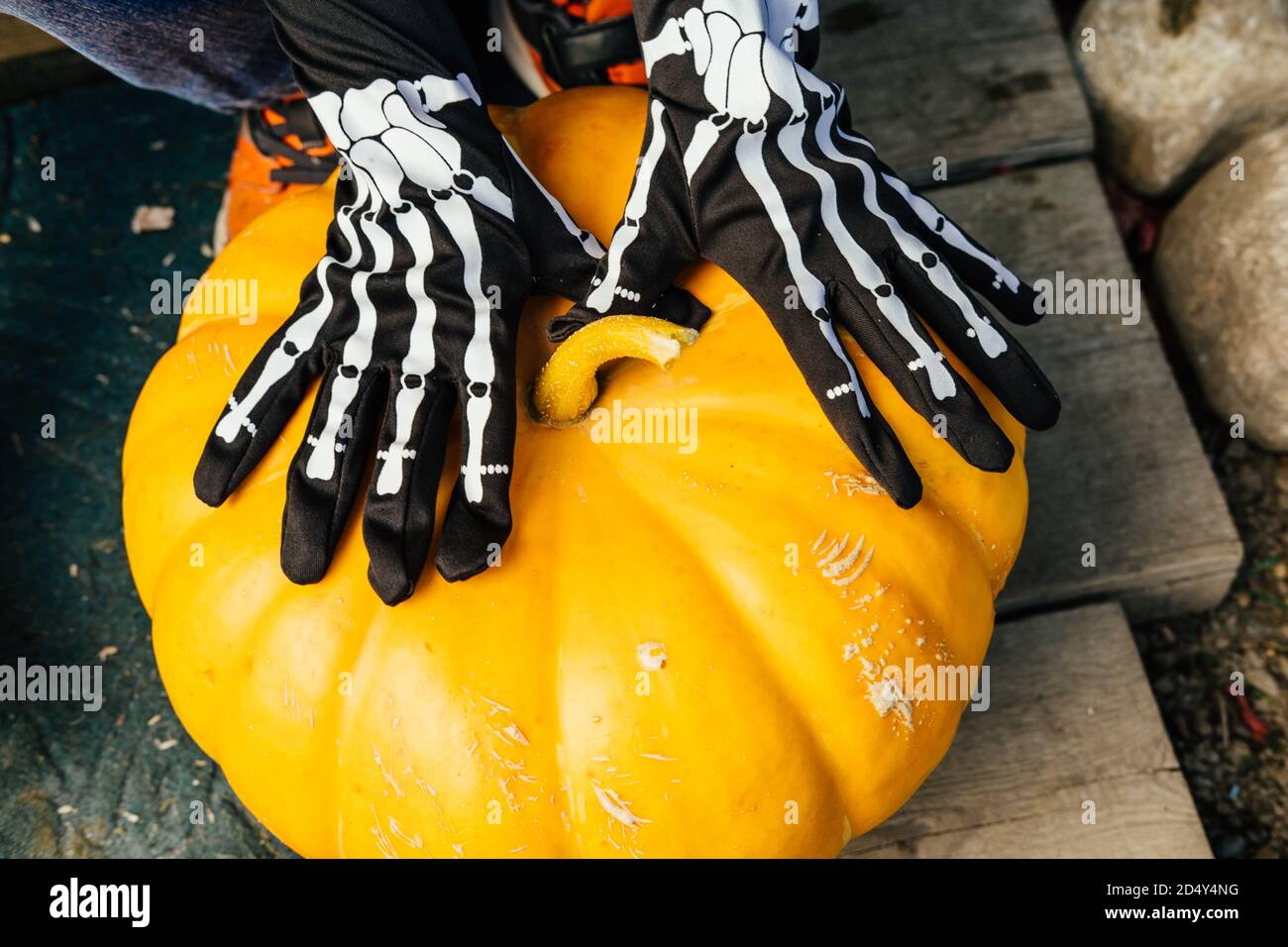 Citrouille avec les mains des enfants dans des gants plus costumés. Joyeux halloween. Banque D'Images