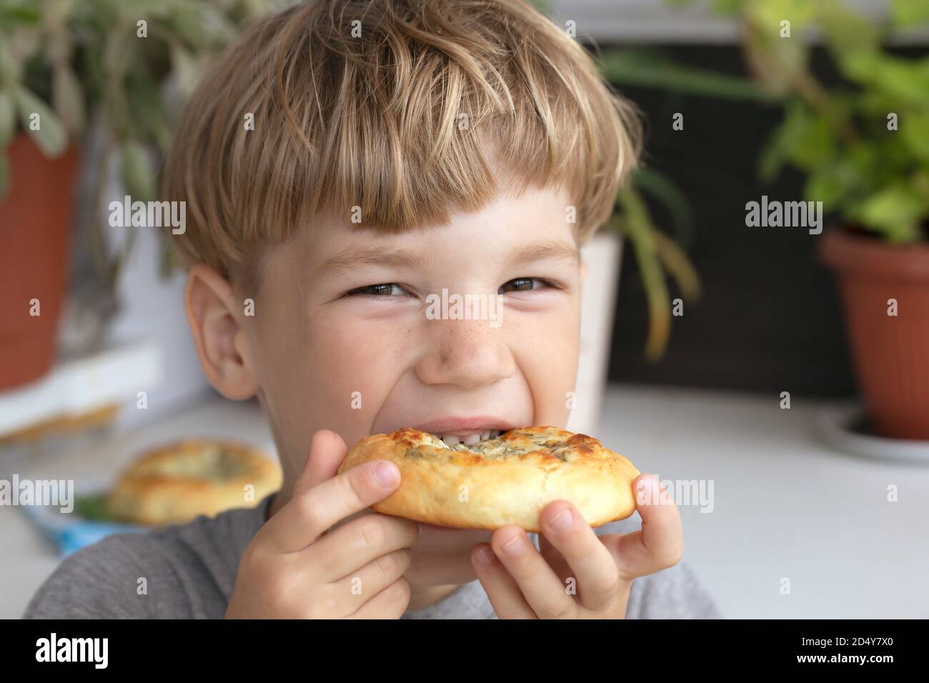 Petit garçon mangeant un beignet. Enfant mangeant de la nourriture de restauration rapide malsaine. Le problème est l'obésité infantile Banque D'Images