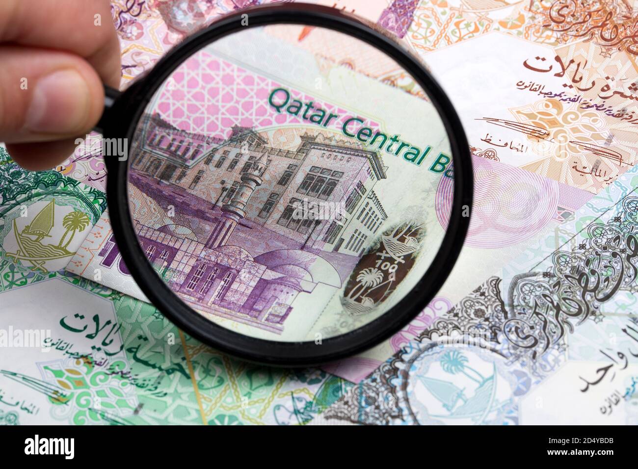 Qatari riyal dans une loupe un arrière-plan d'affaires Banque D'Images