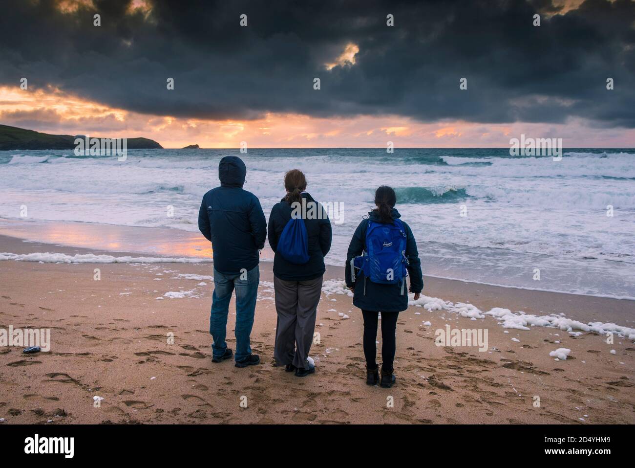 Une famille de vacanciers se tenant sur Fistral Beach et regardant un coucher de soleil spectaculaire à Newquay, dans les Cornouailles. Banque D'Images Une famille de vacanciers se tenant sur Fistral Beach et regardant un coucher de soleil spectaculaire à Newquay, dans les Cornouailles. Banque D'Images