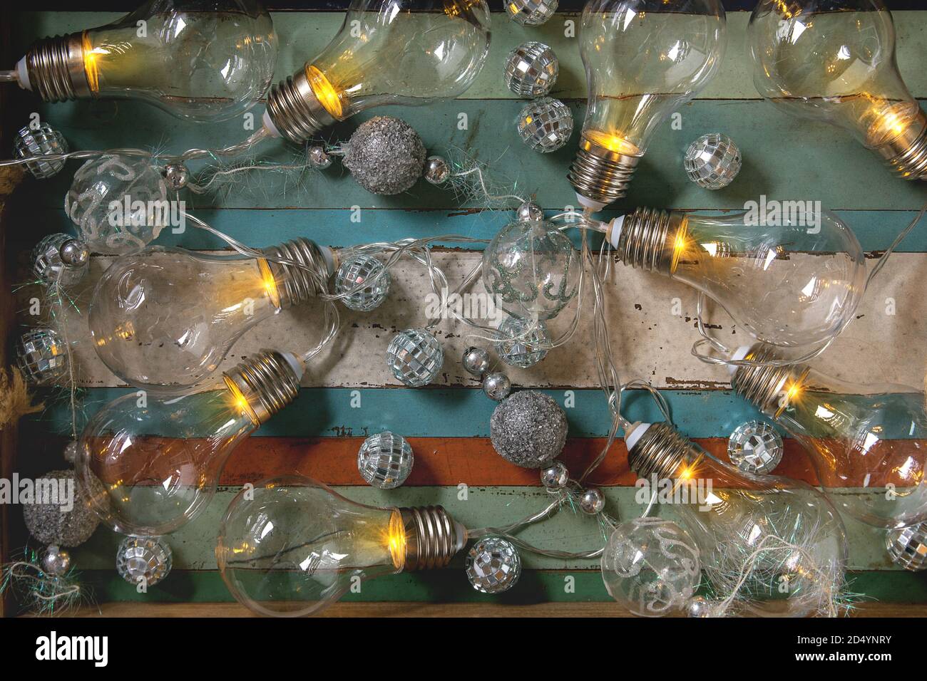 Guirlande de noël rétro éclairé avec des lampes et des boules d'argent sur fond de planches couleur en bois. Mise à plat, de l'espace Banque D'Images