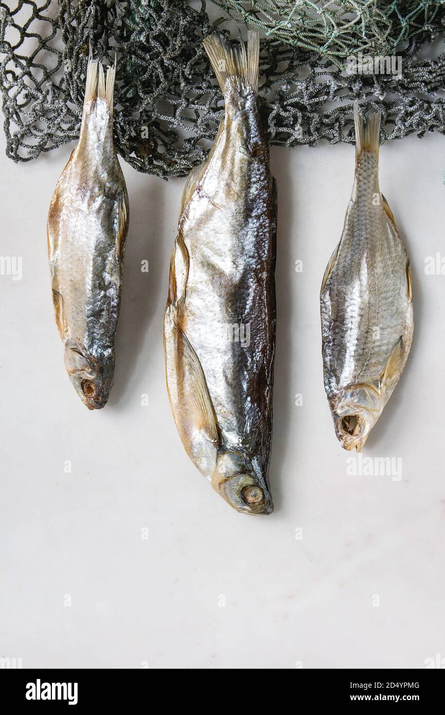 Le poisson séché ou stockfish sur les filets de pêche sur fond de marbre blanc. Mise à plat, de l'espace Banque D'Images