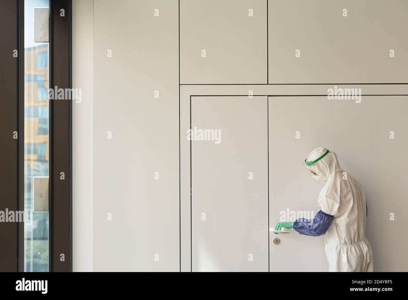 Vue graphique grand angle du travailleur sanitaire portant un costume de nettoyage des poignées de porte dans le bureau, espace de copie Banque D'Images