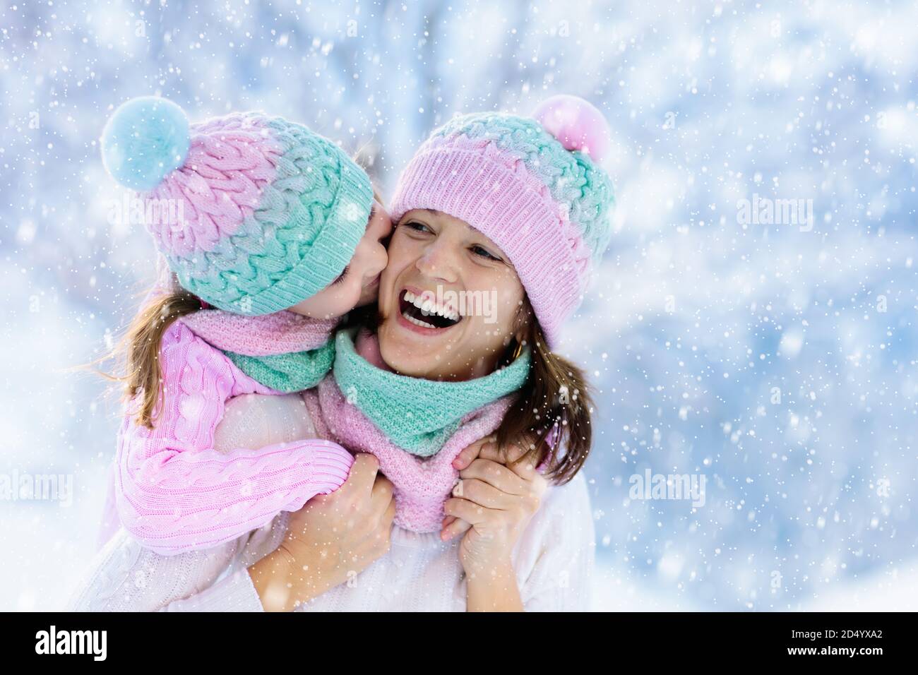 La mère et l'enfant dans l'hiver tricotés chapeaux jouer dans la neige sur  les vacances de Noël. Bonnet et écharpe en laine faits main pour maman et  enfant. Le tricot pour les