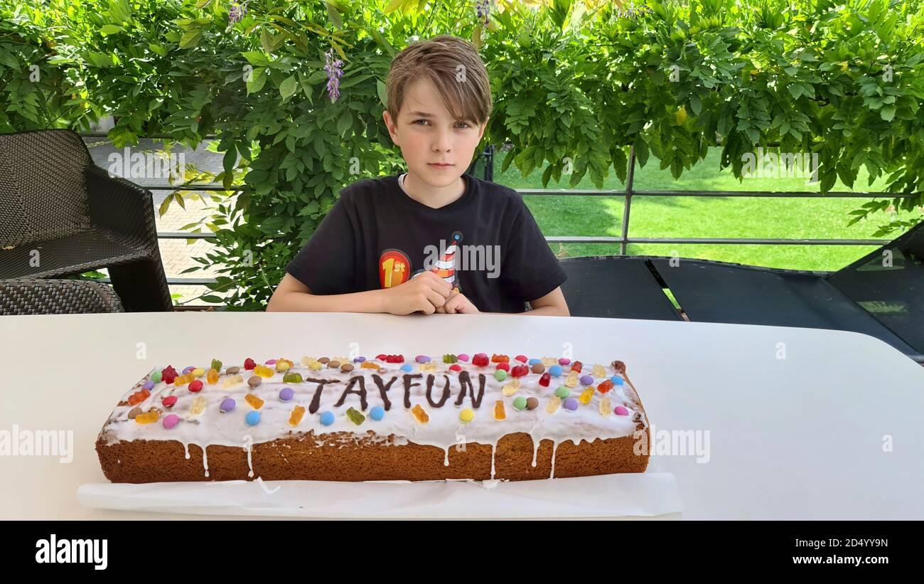 Garçon assis à une table avec son gâteau d'anniversaire, Allemagne Banque D'Images