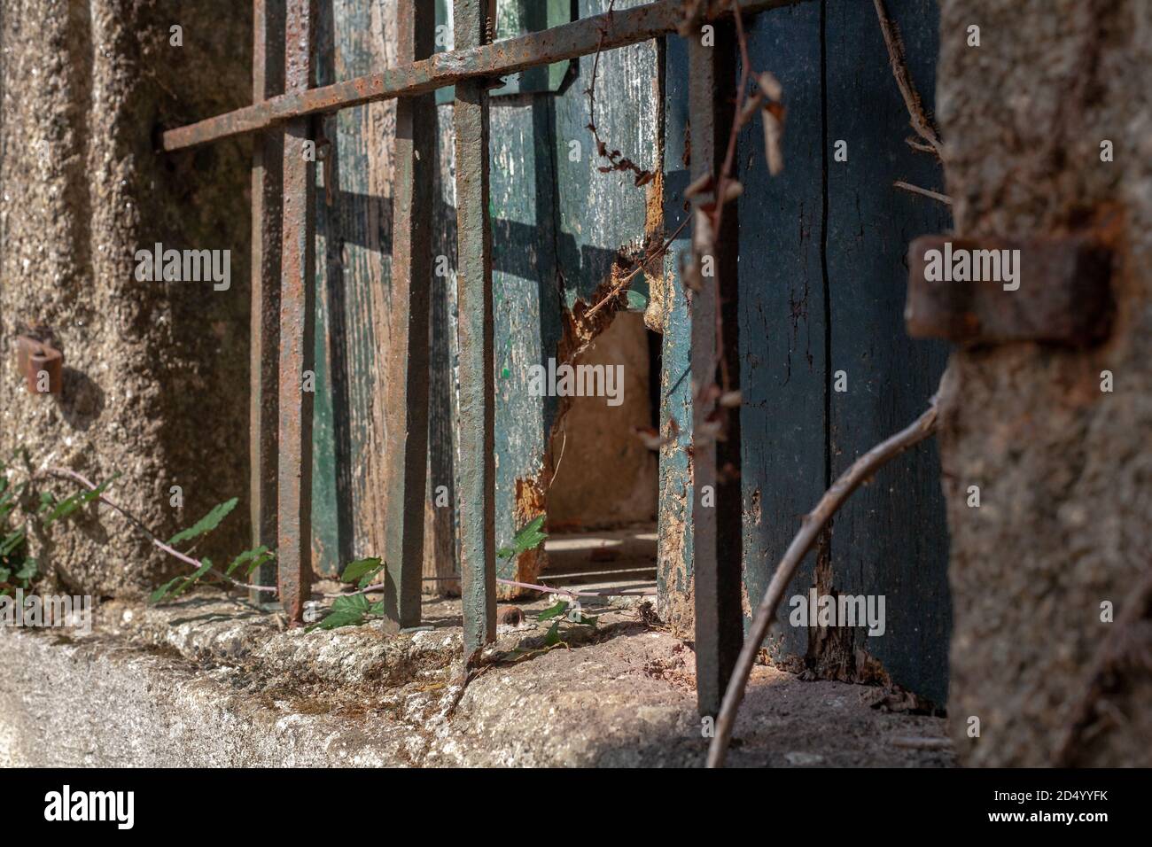 Fenêtre en bois espagnol cassé et usé avec des barres de métal rouillé le recouvrant d'un mur en pierre. Banque D'Images