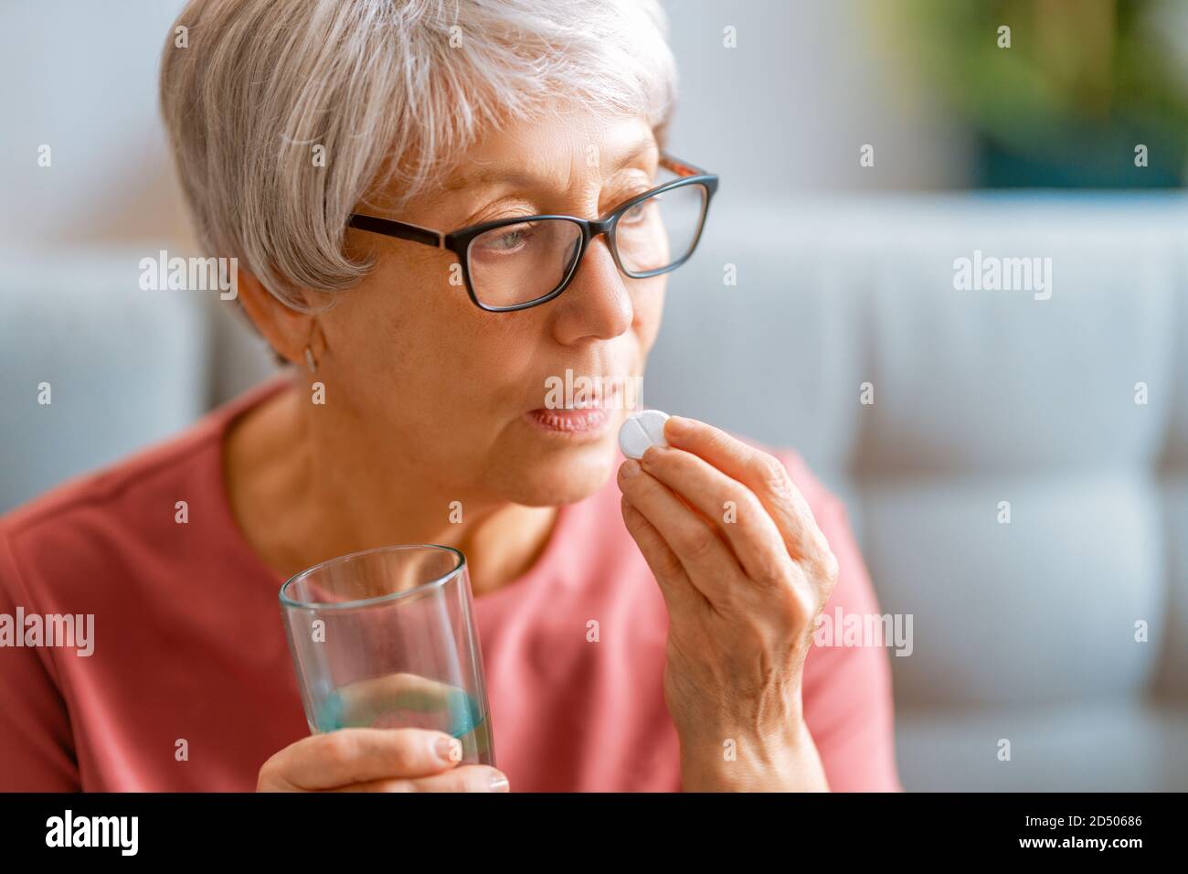 Femme âgée tenant une pilule et un verre d'eau douce, prenant des médicaments contre les maux de tête, les douleurs à l'estomac ou prenant des vitamines, des médicaments de sédation. Banque D'Images