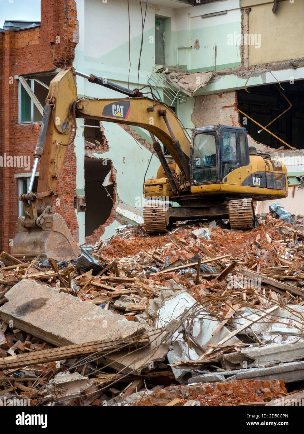 Pelle hydraulique jaune sur le site de démolition, détruit le vieux bâtiment en arrière-plan Banque D'Images