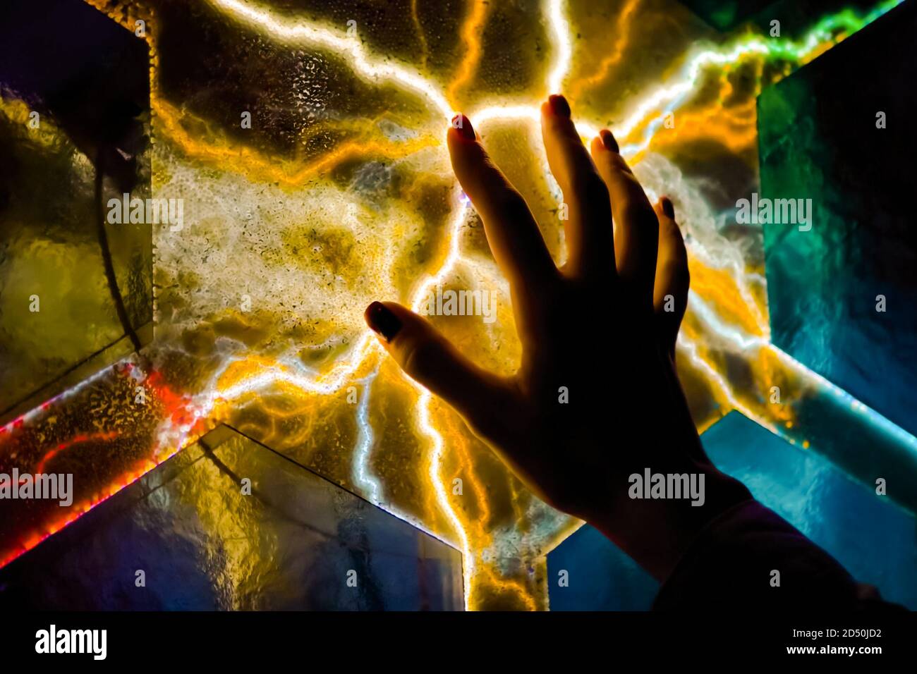 Exposition interactive à écran tactile dans le musée des sciences. Femme à la main touchant l'écran plasma coloré dans la pièce sombre - vue rapprochée. Électricité Banque D'Images