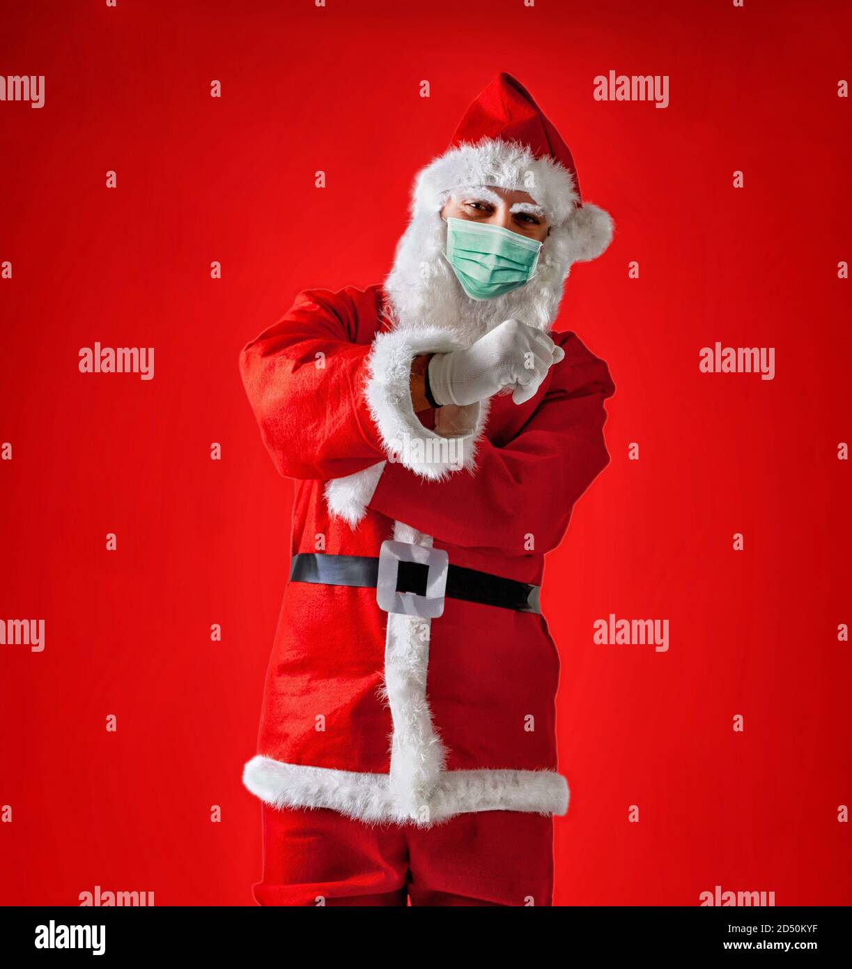 Santa Claus faisant un parapluie italien geste portant le masque chirurgical sur fond rouge. Banque D'Images