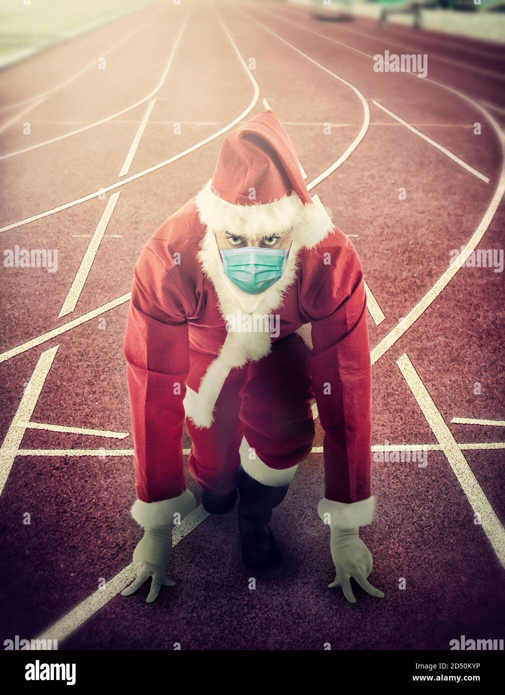 Le Père Noël est en position de départ sur une piste de course portant le masque chirurgical. Banque D'Images