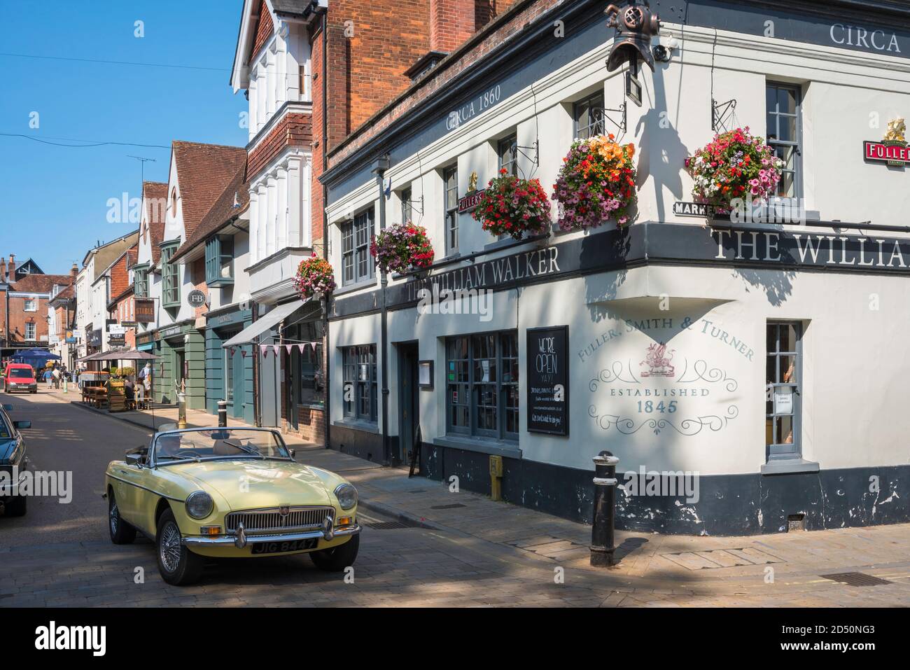 Vue traditionnelle du Royaume-Uni, en été, d'une voiture DE sport MG passant devant un pub à Winchester, Hampshire, Angleterre, Royaume-Uni Banque D'Images