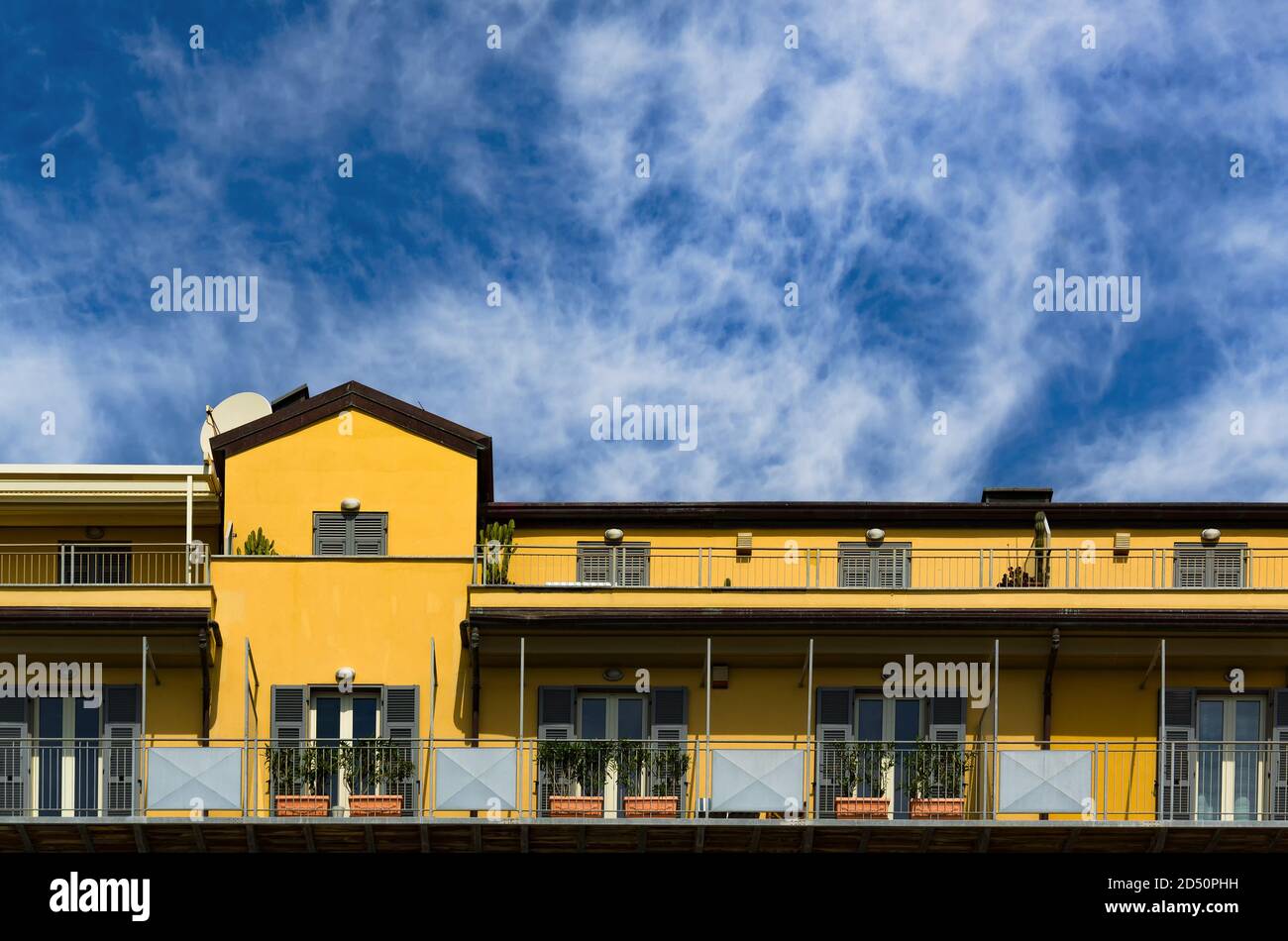 Immeuble d'appartements à Savona, Italie. Façade jaune avec rangées de balcons. Espace de copie sur ciel texturé. Banque D'Images