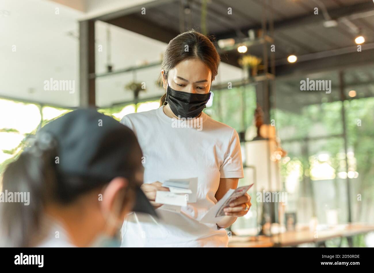 Femme dans la main de masque de protection tenant la réception de facture dans le café. Banque D'Images
