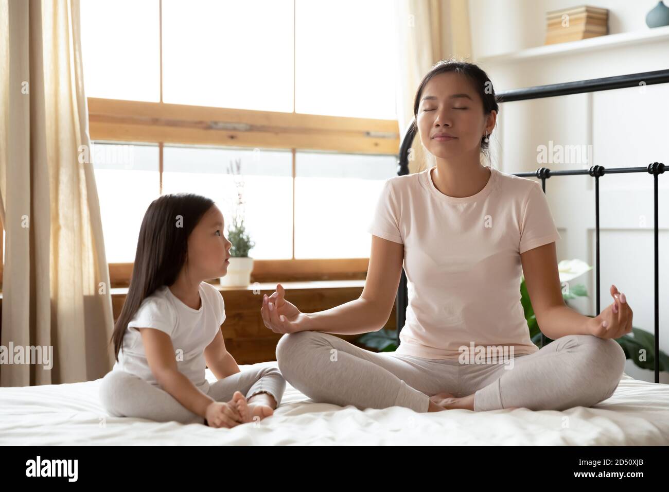 Calme asiatique mère et petite fille faisant des exercices de yoga ensemble Banque D'Images