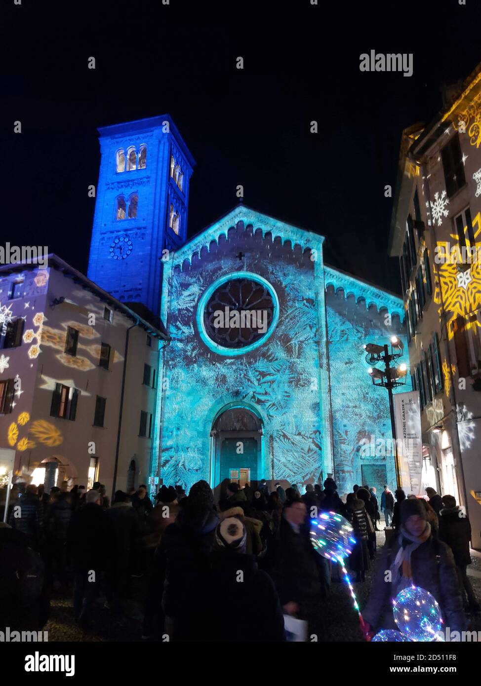 Des lumières de Noël projetées sur la façade d'une église qui ressemble à de la glace et de nombreux flocons de neige qui illuminent les façades des maisons, tout autour de l'homme Banque D'Images