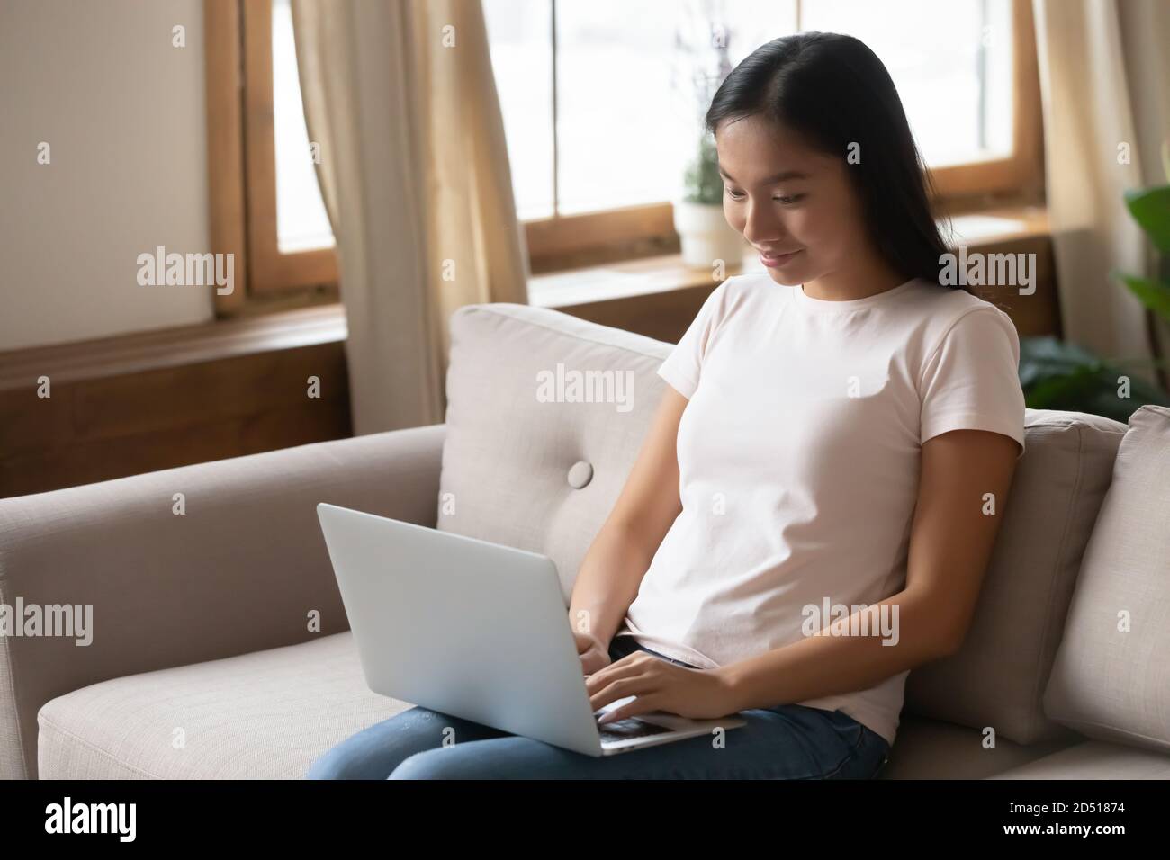 Jeune femme asiatique souriante utilisant un ordinateur portable à la maison Banque D'Images