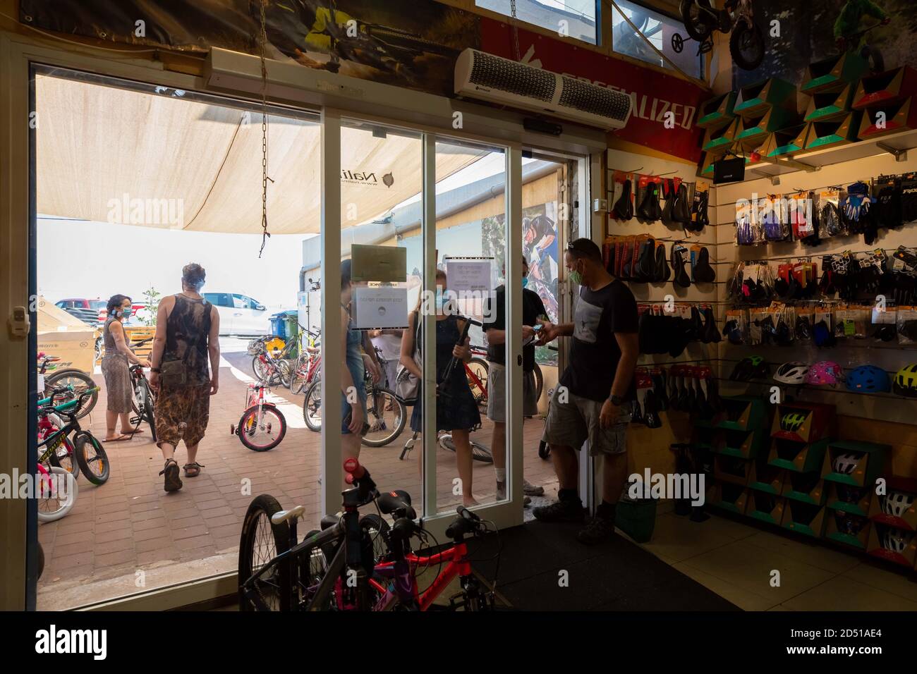 Boutique de vélos pendant la pandémie COVID-19. Les clients attendent à l'extérieur du petit magasin pour le service et sont servis à la porte. Les clients sont obligés de wea Banque D'Images