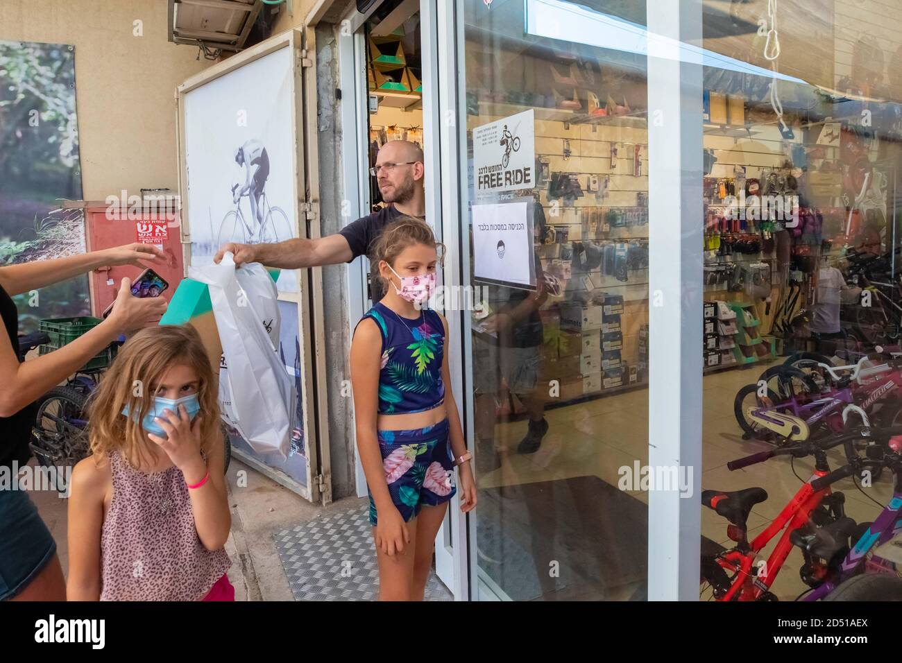 Boutique de vélos pendant la pandémie COVID-19. Les clients attendent à l'extérieur du petit magasin pour le service et sont servis à la porte. Les clients sont obligés de wea Banque D'Images