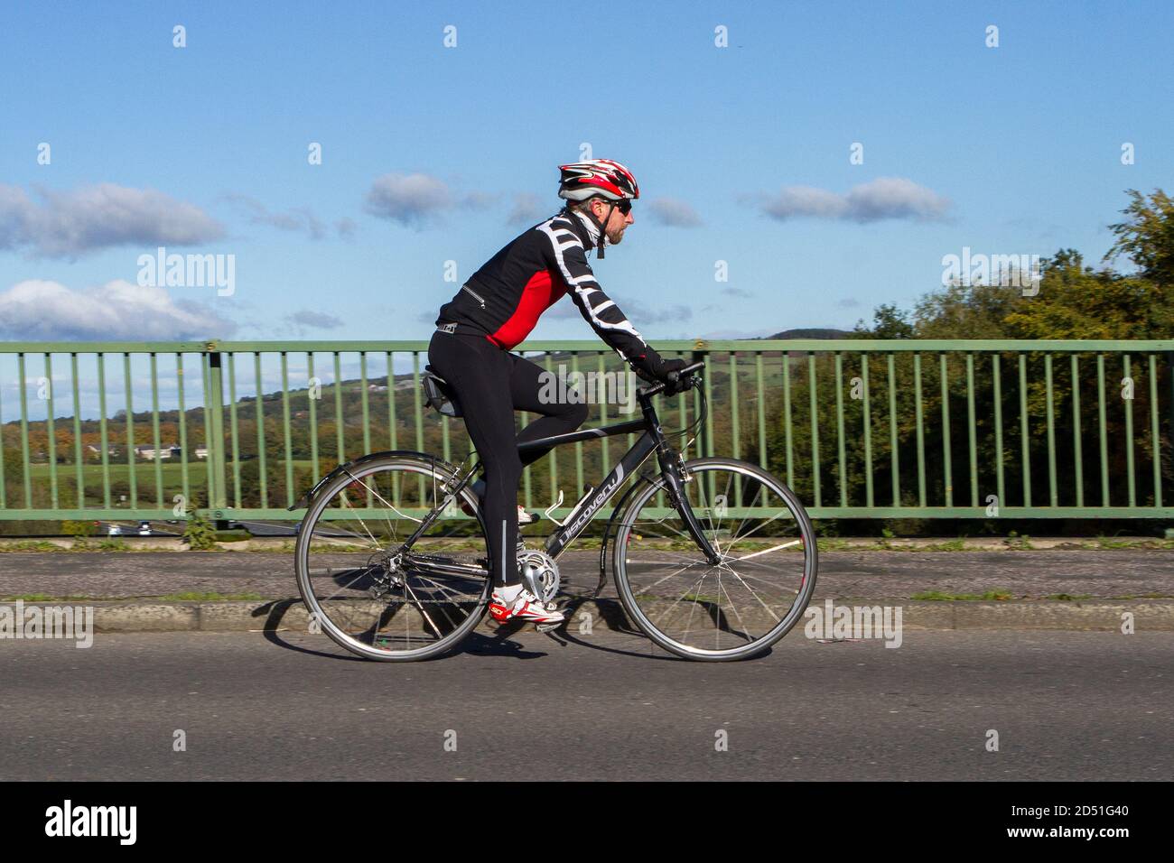 Cycliste de course à pied d'un vélo de route Discovery en fibre de carbone sur une route de campagne traversant un pont autoroutier dans la campagne du Lancashire, au Royaume-Uni Banque D'Images