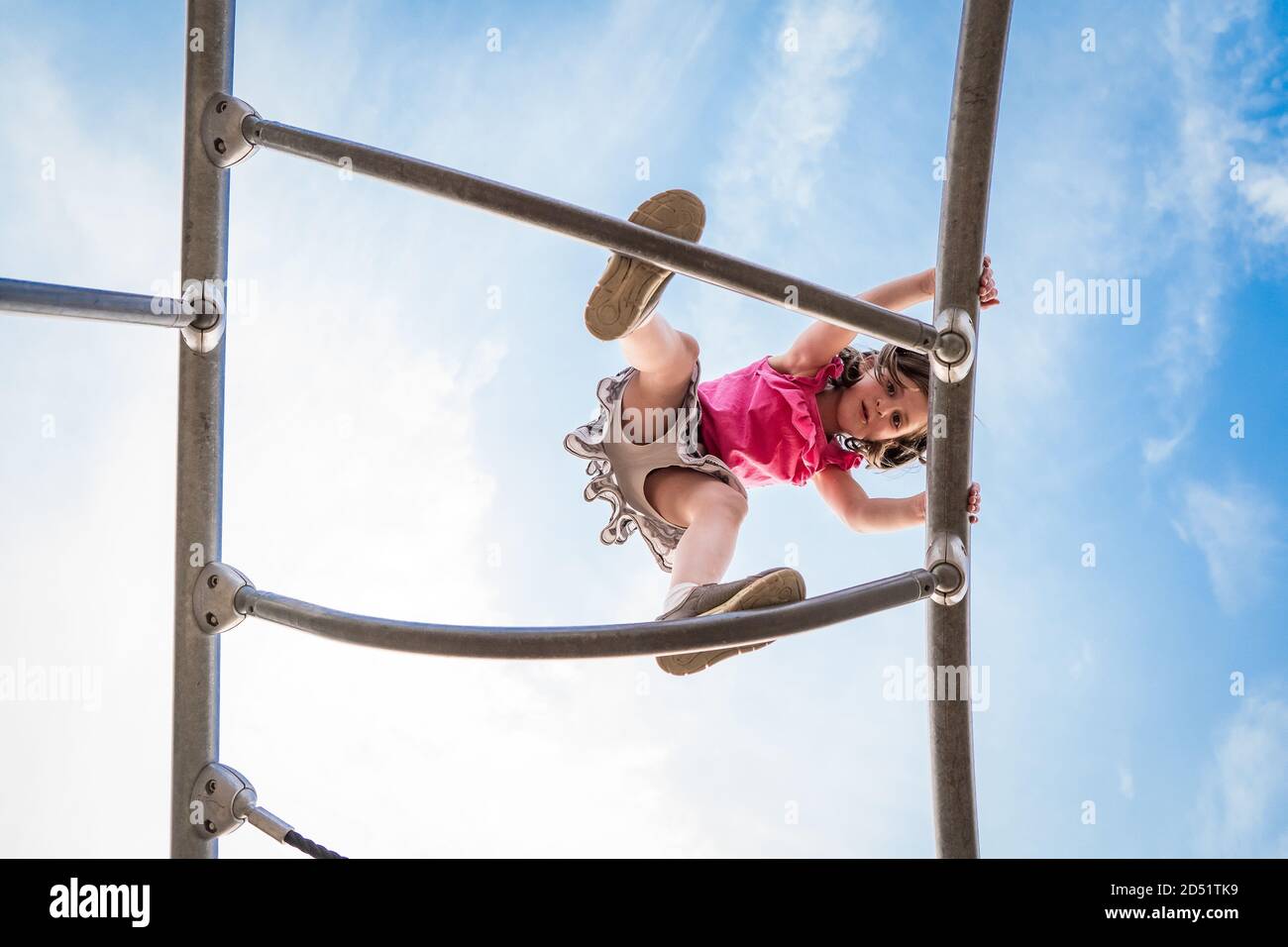 les jeunes filles ont l'air juste en bas d'une structure d'escalade de terrain de jeu Banque D'Images