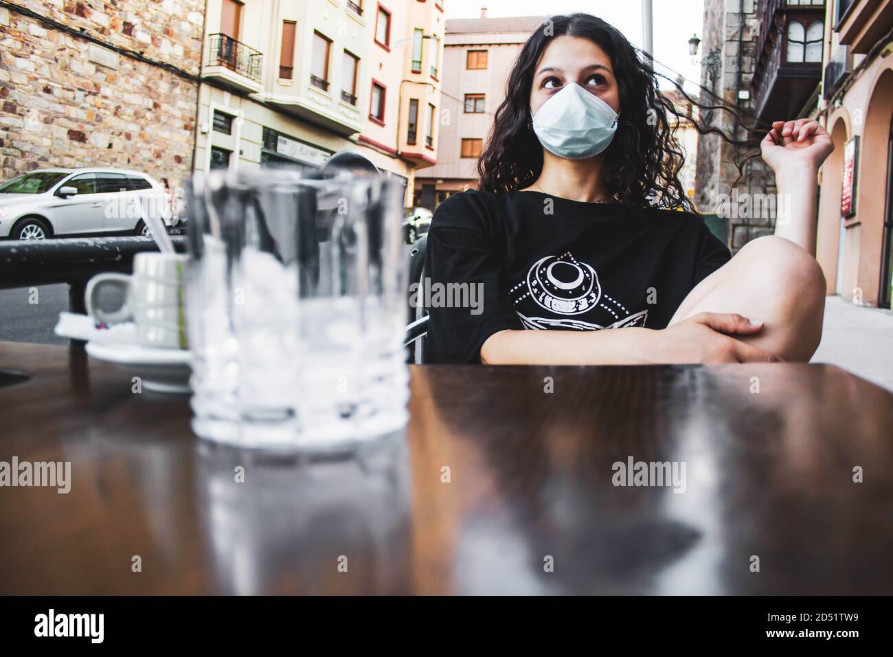 fille ayant un café sur la terrasse d'un bar avec un masque Banque D'Images