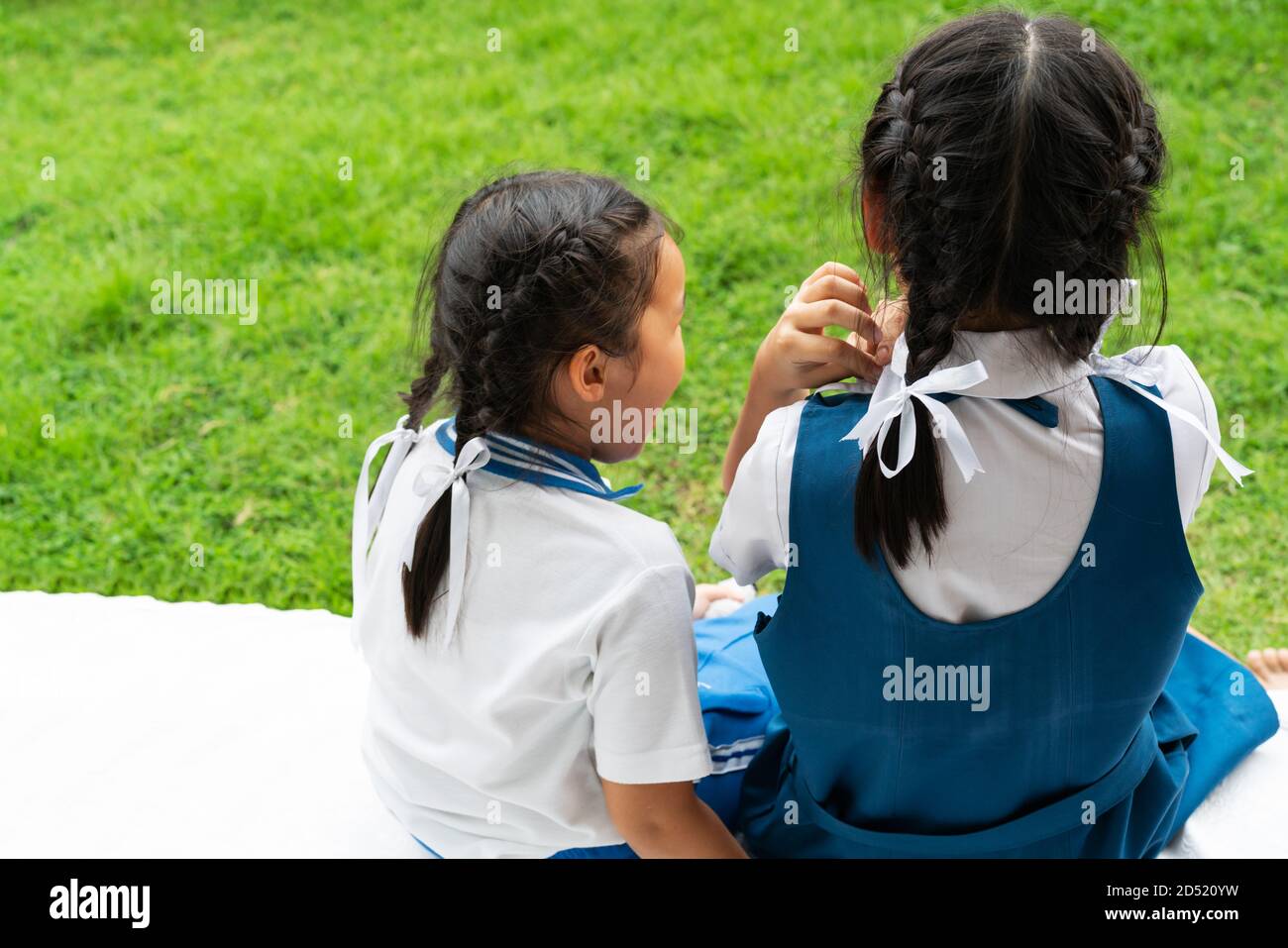 Deux petites filles asiatiques sisters hugging heureux post dans l'uniforme scolaire, concept retour à l'école Banque D'Images