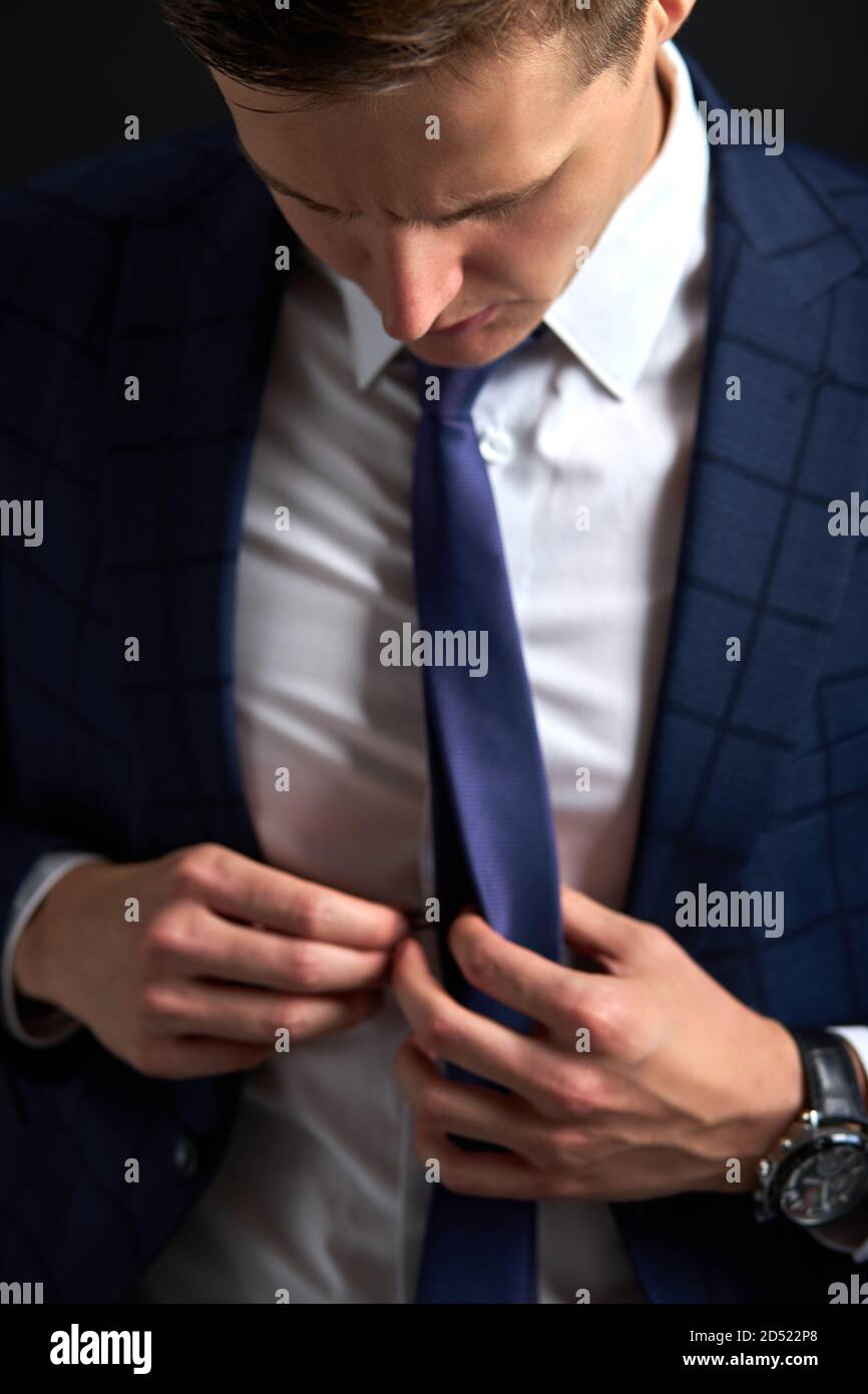 un homme méconnaissable se fixe sur le costume, un homme élégant regarde  sur le cravate, isolé Photo Stock - Alamy