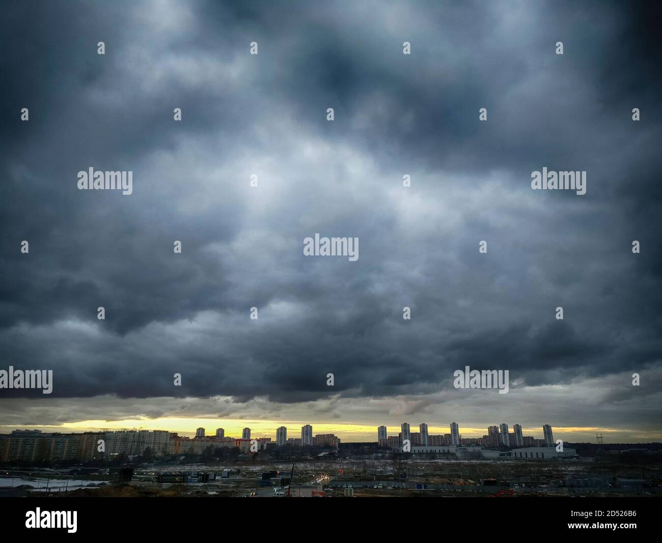 Une tempête suronde la ville. Ciel noir dans les nuages et la ligne du coucher de soleil orange. Zone industrielle sur fond de bourdes imminentes Banque D'Images