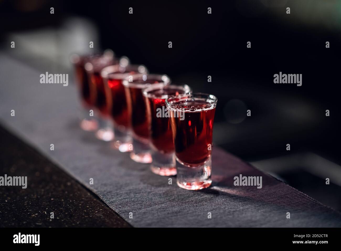 une rangée de prises de vue avec de la liqueur rouge sur le bar du tissu en gros plan. Banque D'Images