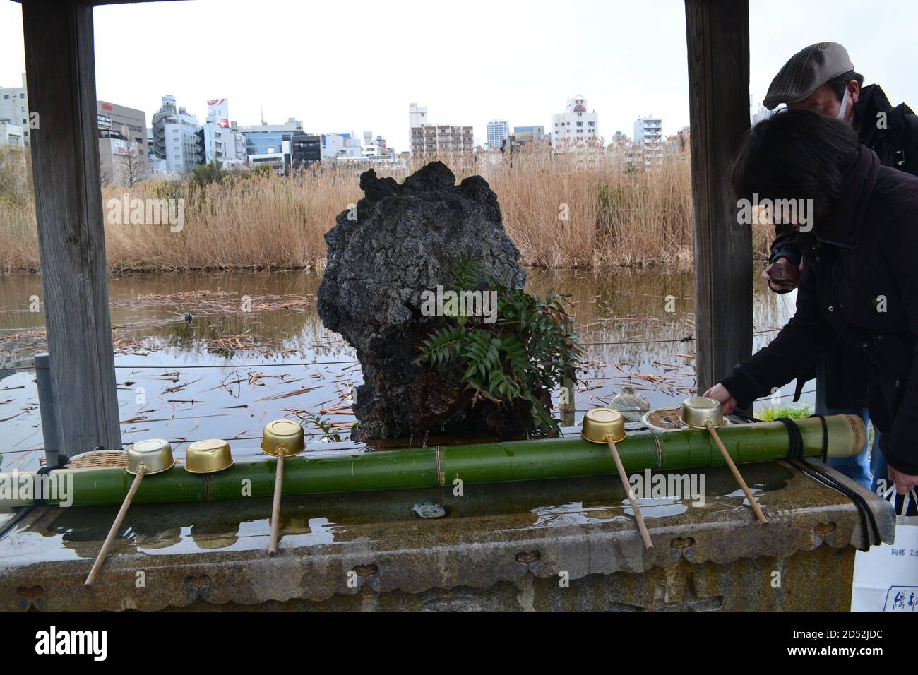 Tokyo, Japon-2/23/16: Un couple interagit avec la fontaine de purification située au sanctuaire Shinobazu-no-ike Bentendo. Banque D'Images